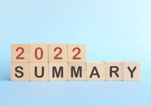 Year end 2022 review and summary concept. Wooden blocks in blue background.